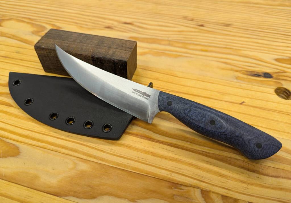 A trailing point knife with blue denim micarta with black micarta pins